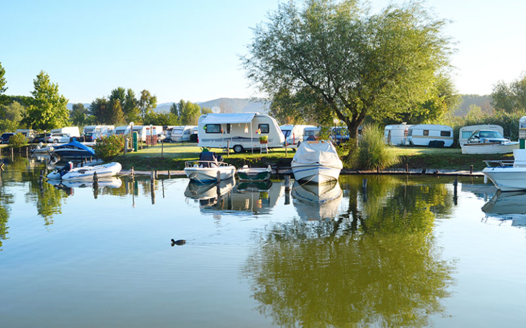 Campingplatz in Thüringen mit mehreren Wohnwagen, Zelten und Booten.
